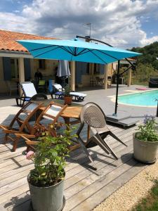 une terrasse en bois avec une table et un parasol bleu dans l'établissement Chambre d'Hôtes Les Bruyères, à Cadouin