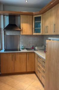 eine Küche mit Holzschränken und einem Kühlschrank aus Edelstahl in der Unterkunft Beach Paradise Apartments in Liepāja