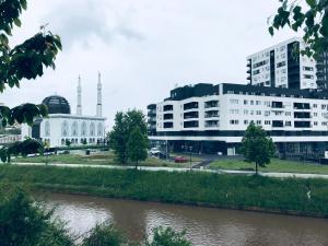 a building next to a river with buildings at Apartman Otoka-Meandar in Sarajevo
