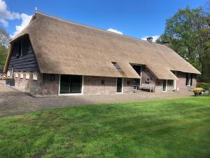Cette grande maison en briques est dotée d'un toit de chaume. dans l'établissement B&B Otterstee, à Havelte
