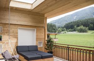 a porch of a wooden house with a swing at Hotel Petrus in Brunico