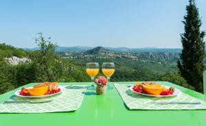 a green table with two plates of food and glasses of wine at Apartman ORLOVAC in Slime +11 photos