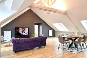 a living room with a purple couch and a table at L'appartement et les Suites de VJL... in Avize