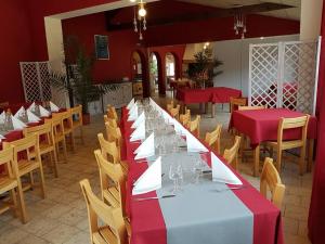 a long dining room with red and white tables and chairs at Les Chênes verts in Saint-Savinien