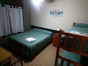 a bedroom with two beds and a table with towels at Hospedaje Champaqui in Santa Rosa de Calamuchita