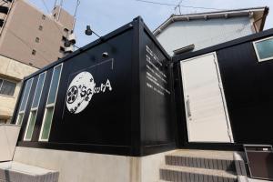 un bâtiment noir avec un panneau sur son côté dans l'établissement SakurA, à Nagoya