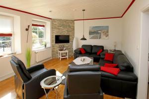 a living room with black leather furniture and red pillows at Ostsee Reetkate in Langballig