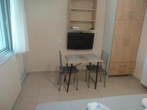a room with a table and two chairs and a television at Despoina Rooms in Tsoukalades