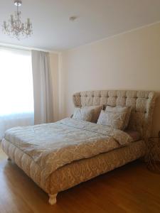 a large bed in a bedroom with a chandelier at Julia apartments next to AQUA PARK in Druskininkai