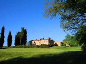 une grande maison sur un champ verdoyant avec des arbres dans l'établissement Agriturismo Natura E Salute, à San Gimignano