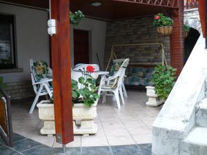 ミシュコルツ・タポルツァにあるKitty Apartmanのパティオ(白い椅子、赤い花のテーブル付)