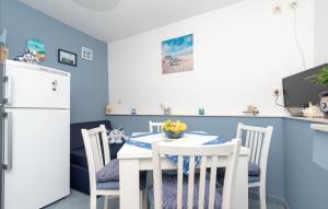 a kitchen with a white table and chairs and a white refrigerator at Apartman Sunrise in Vela Luka