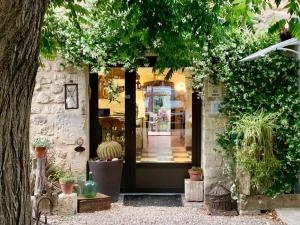 een voordeur van een winkel met potplanten bij Logis Hotel Restaurant Hostellerie de la Tour in Fontvieille