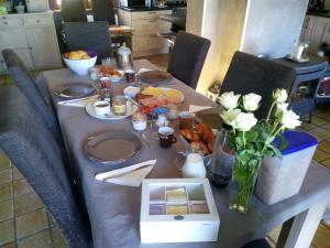 a table with plates and flowers and a laptop on it at Votre Horizon in Aywaille