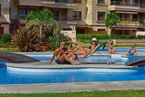 a group of people sitting around a swimming pool at Nuevo Ático Isla de la Toja in Isla de la Toja