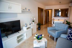 a living room with a flat screen tv and a blue chair at Apartment las sirenas WiFi 100 Mb in Roquetas de Mar