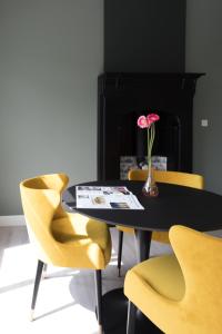 a table with yellow chairs and a vase with a flower on it at B&B de Lijsterhof in Domburg