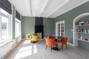 B&B de Lijsterhof في دومبورغ: غرفة طعام مع كراسي برتقالية وطاولة