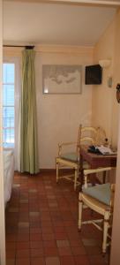 een kamer met 2 stoelen, een tafel en een televisie bij Auberge des Glycines in Porquerolles