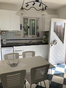 a kitchen with white cabinets and a table and chairs at Apartmani ROBERTA in Bol