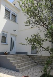 a white building with stairs in front of it at Mesić Apartment in Senj