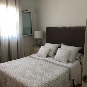 ein Schlafzimmer mit einem Bett mit zwei Kissen und einem Spiegel in der Unterkunft ATICO SAN MARCOS in El Puerto de Santa María