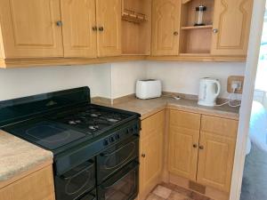 a kitchen with a green stove and wooden cabinets at Private Countryside Holiday Cabin 10 mins from Brighton in Brighton & Hove