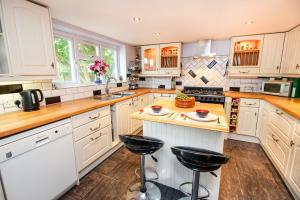 a large kitchen with white cabinets and bar stools at Mallard Cottage Guest House in Aylesford