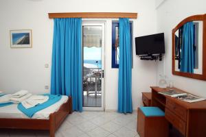 a bedroom with a bed and a window with blue curtains at Kathisma Studios Apartments-Theochari Angeliki GP in Agios Nikitas
