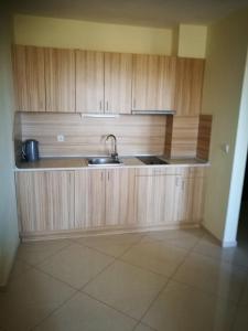 a kitchen with a sink and wooden cabinets at Aparthotel Afrodita 2 in Sinemorets