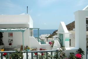 Blick auf ein weißes Gebäude mit Blumen und das Meer in der Unterkunft Kalypso House in Pera Gyalos