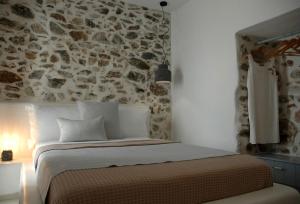 Bett in einem Zimmer mit einer Steinmauer in der Unterkunft Kalypso House in Pera Gyalos