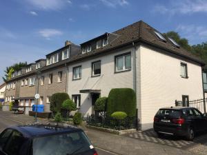 una gran casa blanca con coches estacionados frente a ella en Messewohnung Düsseldorf en Düsseldorf