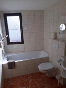 a bathroom with a tub and a toilet and a window at Hotel Garni Alpenruh-Micheluzzi in Serfaus
