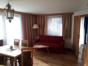 a living room with a red couch and a table at Hotel Garni Alpenruh-Micheluzzi in Serfaus