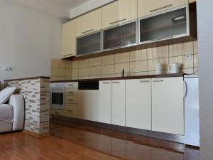 a kitchen with white cabinets and a brick wall at Apartman Ćorić Posušje in Posušje