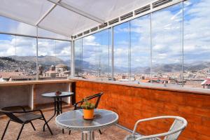 a patio with tables and chairs and large windows at The Chusay Rooftop in Cusco