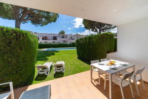 a patio with a table and chairs and a garden at Holiday Home Gardenia in L'Escala