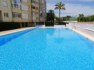 a large blue swimming pool in front of a building at ROMA 11 GANDÍA - Alquiler a familias in Gandía