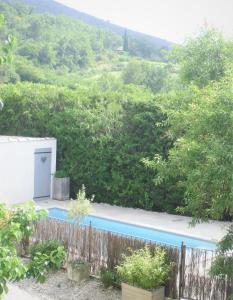 MéthamisにあるGîte de charme piscine et SPA en Provenceの塀と木のあるスイミングプール