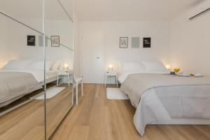 a white bedroom with two beds and a glass wall at Enjoy Split in Split