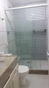 uma casa de banho com um WC e uma cabina de duche em vidro. em Apartamento em Resort em Barreirinhas