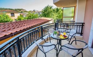 a balcony with two chairs and a table with fruit on it at Konstantina & Evgenia Deluxe Apartment in Nea Peramos