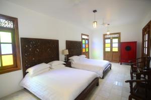 two beds in a room with chairs and windows at Lanna Ban Hotel in Puerto Viejo