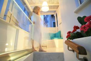 a woman in a white dress walking down the stairs at Lasia Boutique Apartment in Andros