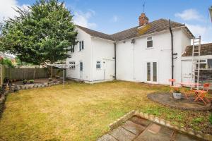 une arrière-cour d'une maison blanche avec une table et des chaises dans l'établissement Mallard Cottage Guest House, à Aylesford
