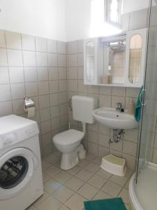 W łazience znajduje się toaleta, umywalka i pralka. w obiekcie Cs&M Vendégház Gyenesdiás w Gyenesdiás