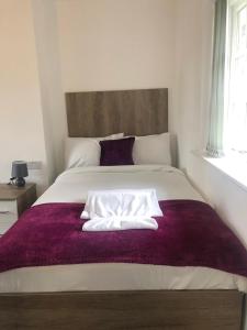 a bedroom with a large bed with a purple blanket at Lancaster Place Apartments in Leicester