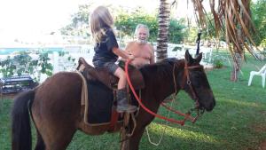 a man and a little girl riding on a horse at POUSADA SERRA DA CANASTRA in Delfinópolis