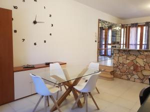 a dining room with a glass table and white chairs at Casa vacanze Valentina in Porto Conte
